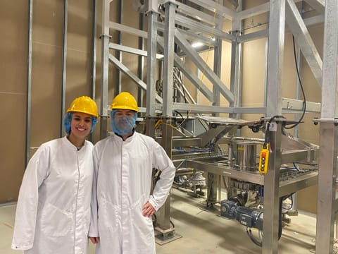 Two colleagues in hard hats at the production line